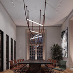 A Clérachic pendant with dark leather loops hung above a long table in a room lit by wall-mounted tracks.