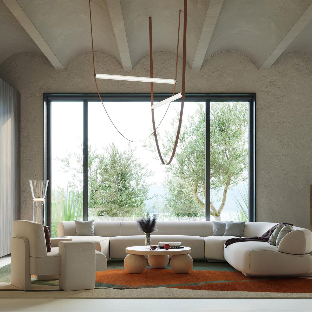 This Clérachic pendant hangs in a living room with a vaulted plaster ceiling and a big window onto olive trees.