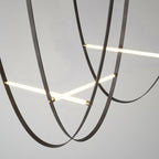 Close view of black leather loops crossing two lit bars on this Clérachic pendant, against a pale grey backdrop.