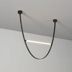 A black leather version of this Clérachic pendant, with black canopy plates and one lit bar across the loop, against a plain wall.