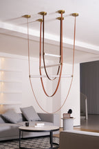 This Clérachic pendant hung in a pale living room, its leather loops and unlit bars reaching down past a coffee table and sofa.