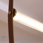 Close view of a brass button fixing a leather strap to the glowing ribbed tube of this Clérachic pendant.