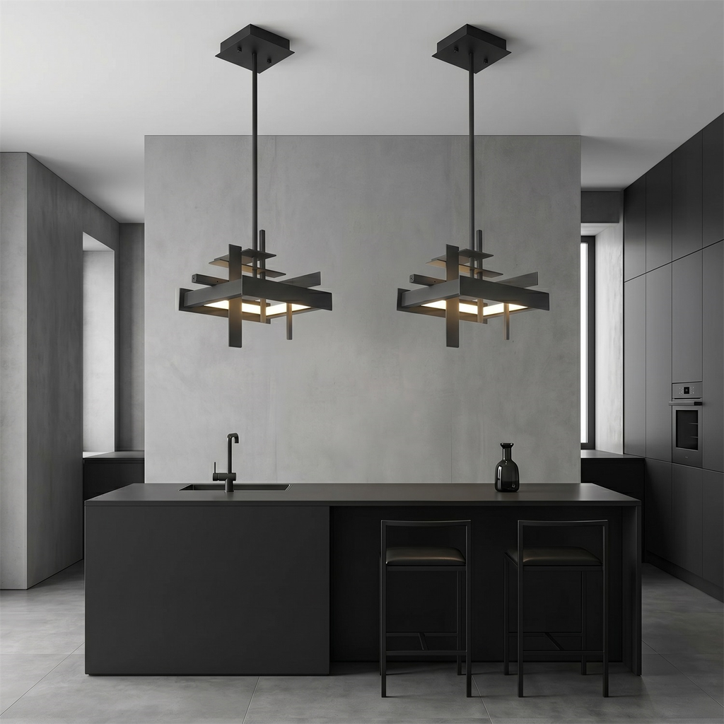 Two compact black geometric Clérachic pendants hang above a black kitchen island with bar stools, against a grey concrete-look wall.