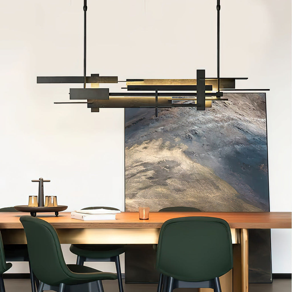 A wide dark Clérachic pendant with layered, offset bars glows warm above a timber dining table with dark green chairs and a large painting.