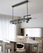 A linear matte black Clérachic pendant on two rods and a ceiling bar hangs above a stone dining table with pale boucle chairs.