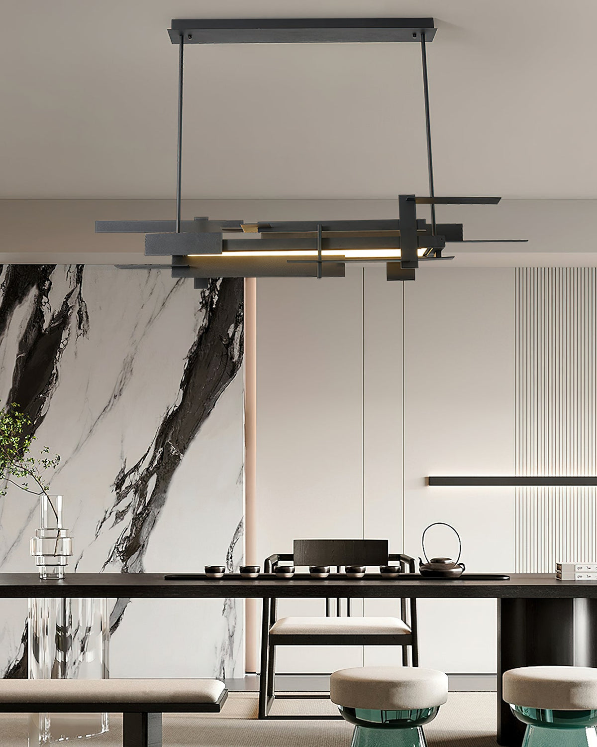 A black linear Clérachic pendant hangs in front of a marble-effect wall above a dark dining table with a tea set.