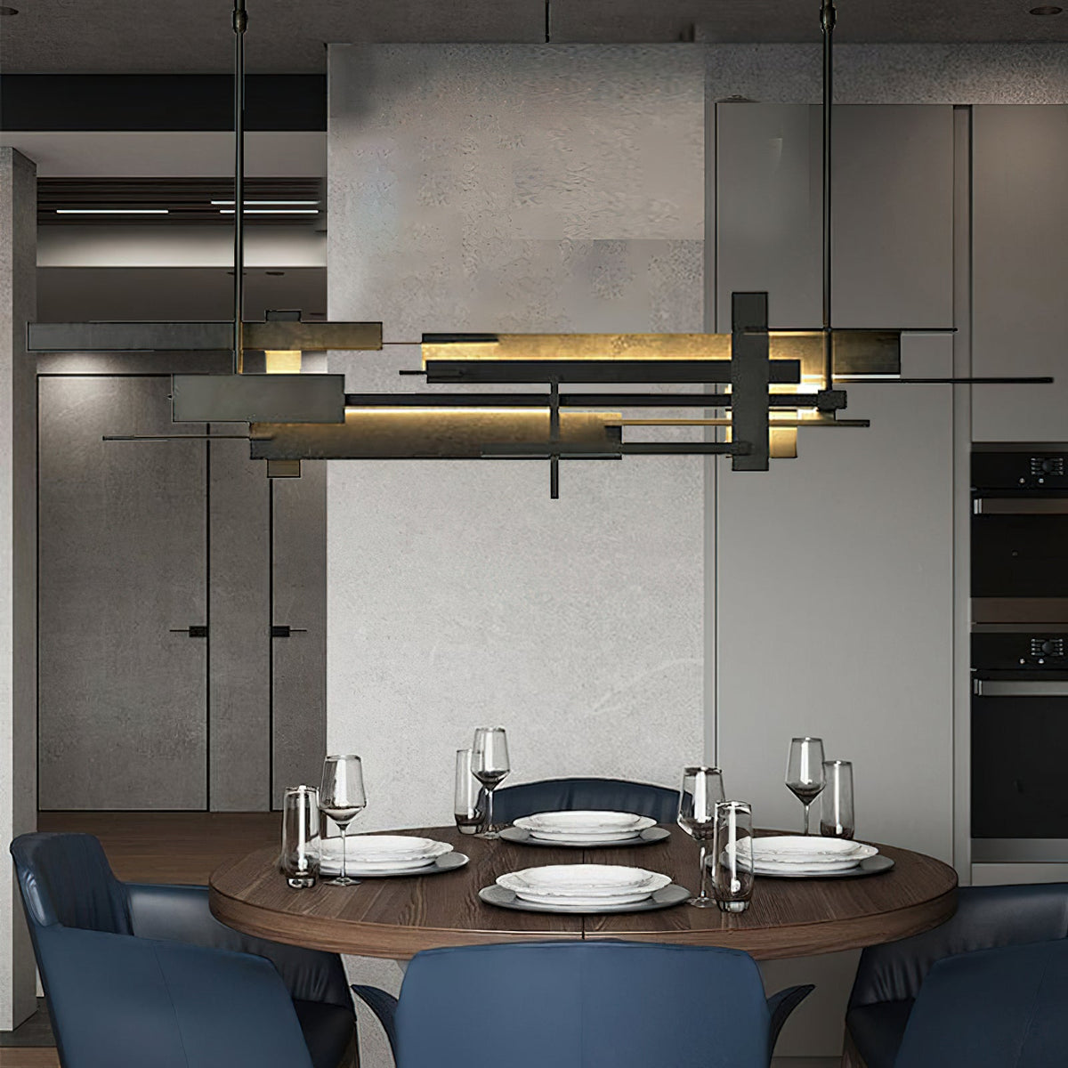 A long dark Clérachic pendant with layered bars and a warm lit strip hangs above a round table laid for dinner, in a grey kitchen.
