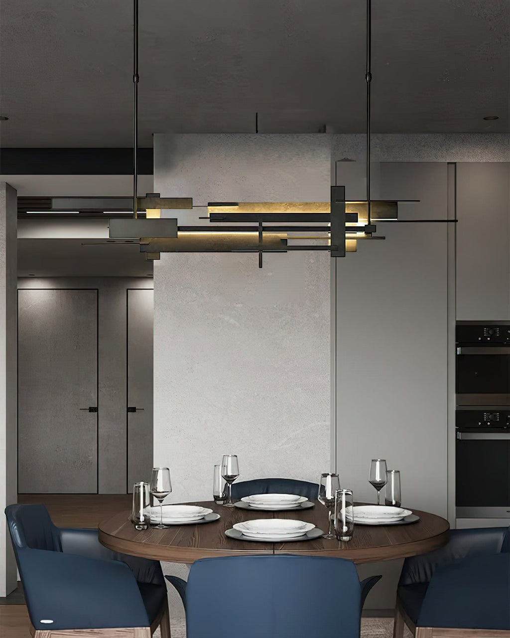 A long dark Clérachic pendant with layered bars hangs in a grey dining room above a round table set with plates and glasses.