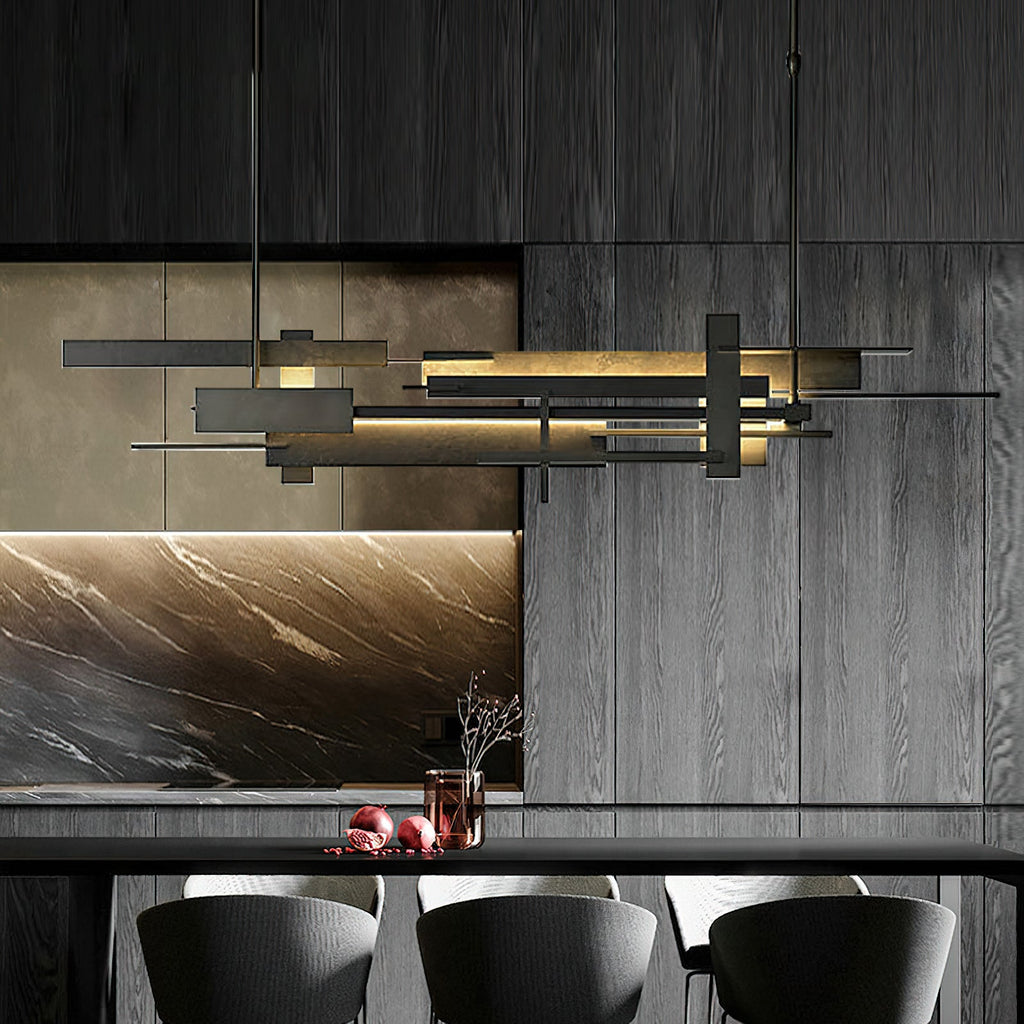 A long dark Clérachic pendant with layered bars hangs in front of dark wood panelling and a marble splashback above a counter.
