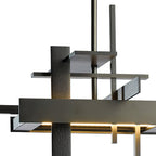 Close view of the textured dark metal bars of this Clérachic pendant, with a warm glow along the underside of the lowest bar.