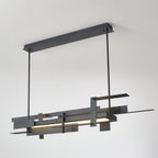 A long matte black Clérachic pendant lit along its lower bar and hung from a ceiling bar, on a pale backdrop.