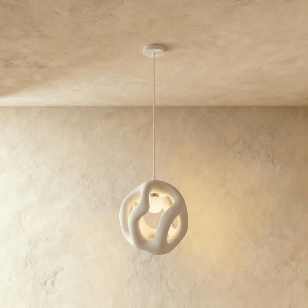 Clérachic white openwork pendant light on a white cord, its organic looped form lit from within against warm plaster.