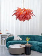 Warm light glows through the coral feathers of this Clérachic chandelier, hung above a teal sofa and a pair of low tables.