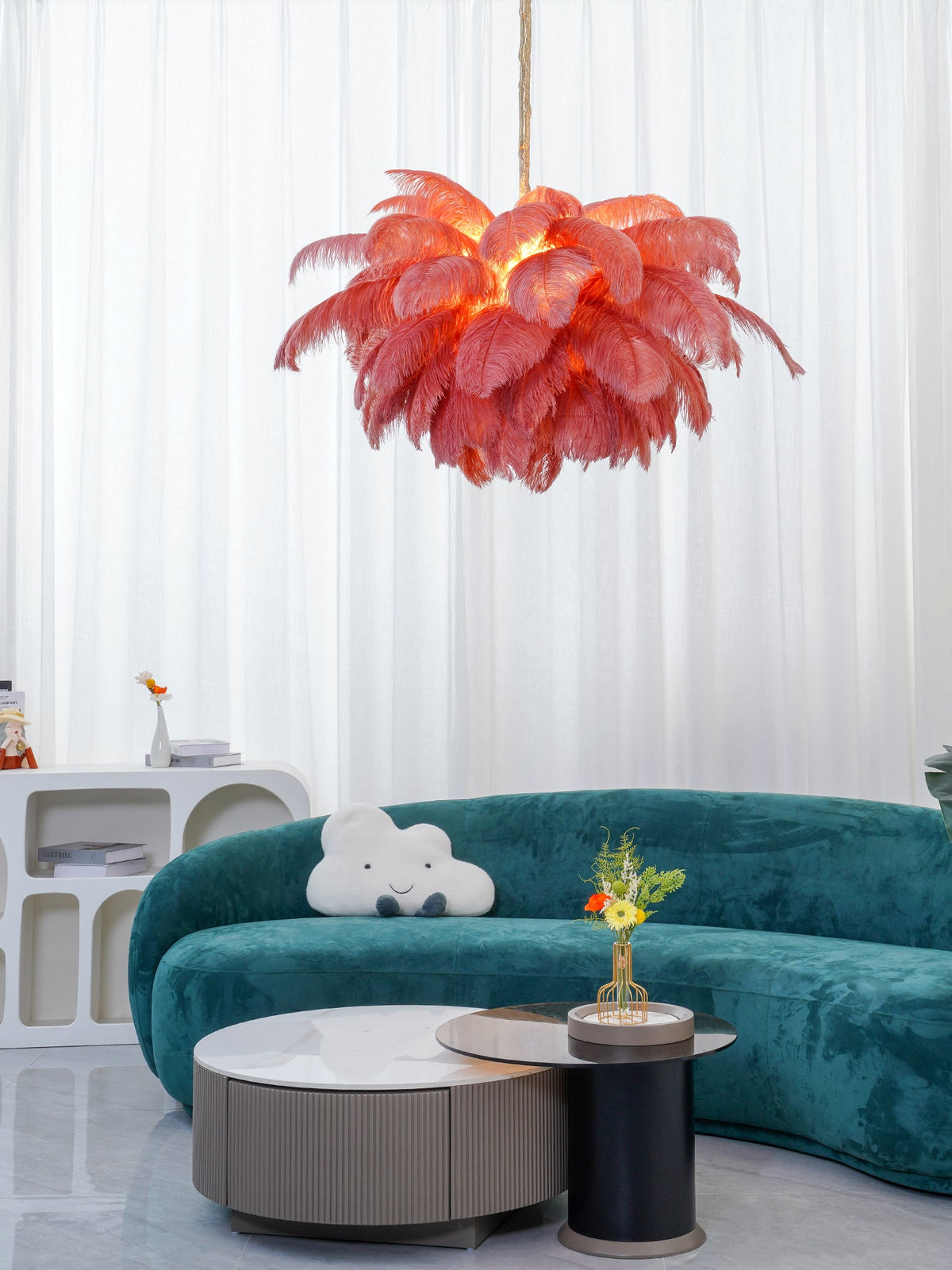 Warm light glows through the coral feathers of this Clérachic chandelier, hung above a teal sofa and a pair of low tables.