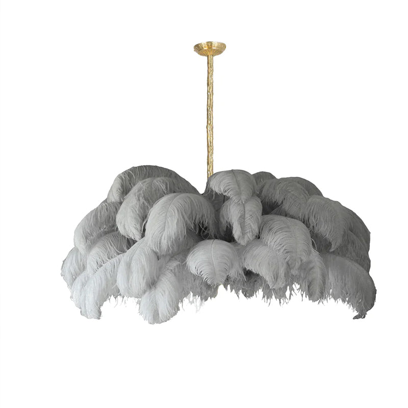 Light grey feathers cascade in thick layers from the brass stem of this Clérachic chandelier, shown on white.