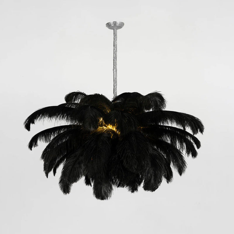 A black-feather Clérachic chandelier is lit at the centre, hung from a silver-finish stem against a pale grey backdrop.