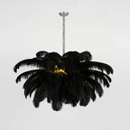 A black-feather Clérachic chandelier is lit at the centre, hung from a silver-finish stem against a pale grey backdrop.
