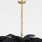Close view of the carved brass stem and round ceiling canopy of this Clérachic chandelier, with black feathers below.