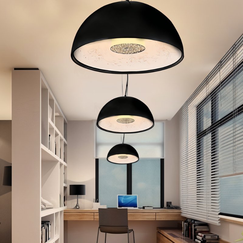 Three Clérachic black dome pendant lights in graduated sizes hanging in a bright home office with shelving.