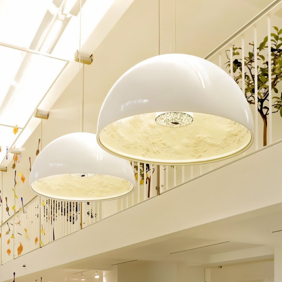 Two large Clérachic white dome pendant lights hung beside a mezzanine balustrade, lit warm from within.