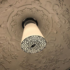 Clérachic ceiling light with a white cone shade and cut-metal filigree diffuser set in a plaster ceiling rose.