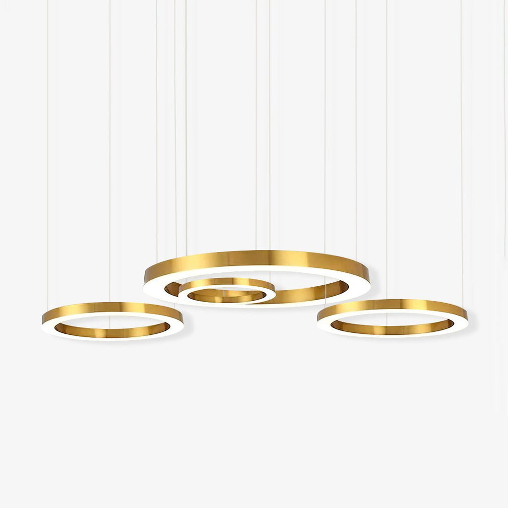 Four gold rings of different diameters hang at staggered heights on thin cables against a white backdrop, on this Clérachic ring pendant.