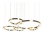 Five polished gold rings of different diameters hang from fine cables on a white backdrop, with the glowing inner faces of this Clérachic pendant.