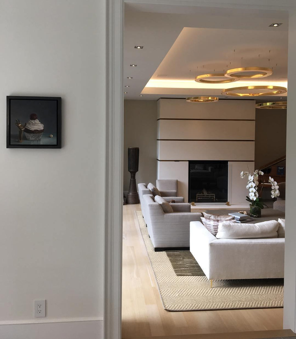 A view through a doorway to a living room where a cluster of gold rings glows under a lit ceiling recess, with this Clérachic ring pendant.