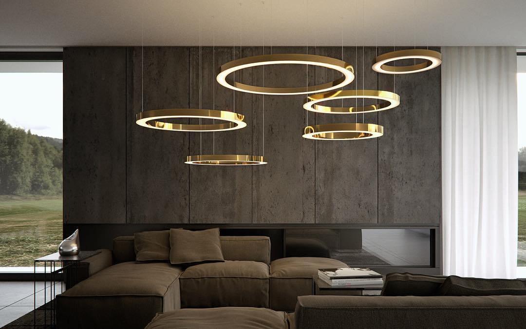 Gold rings hang at staggered heights over a dark lounge with a stone-clad wall and a window onto trees, lit by this Clérachic pendant.
