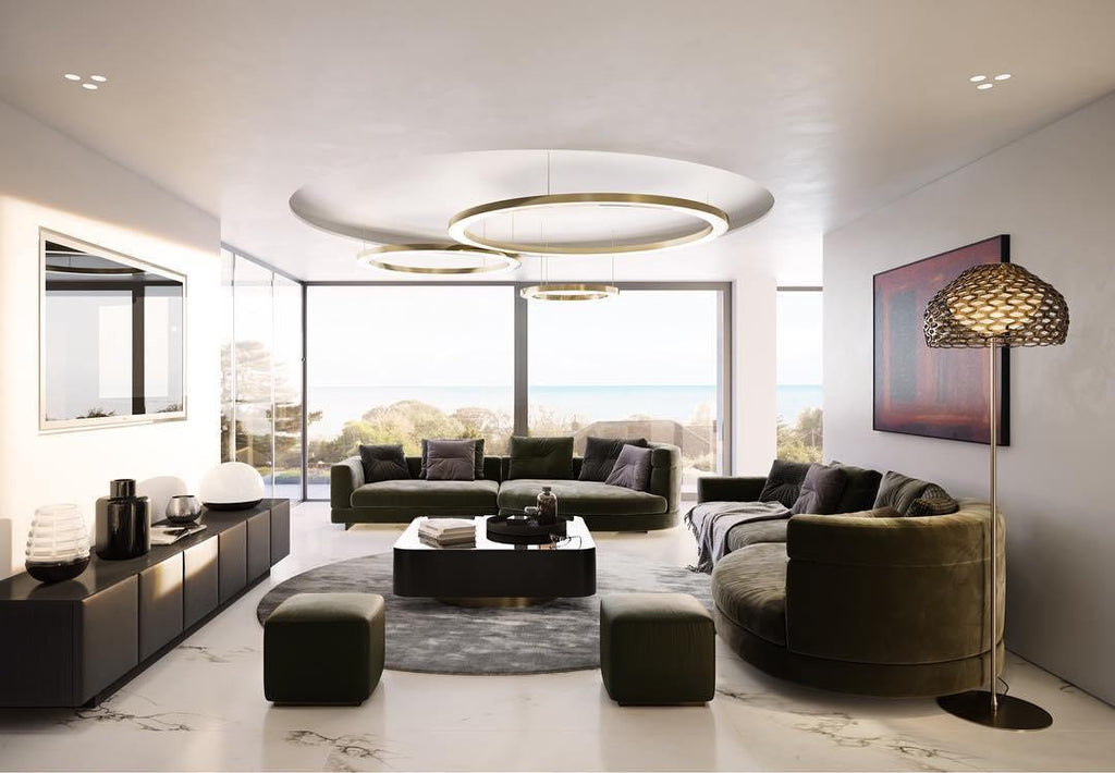 Gold rings hang over a recessed round ceiling panel in a living room with olive velvet sofas and a sea view, lit by this Clérachic pendant.
