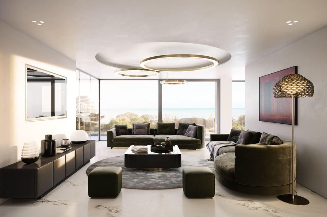 A bright living room with olive sofas and a sea view, the Clérachic ring pendant hanging in gold rings from a round ceiling recess.