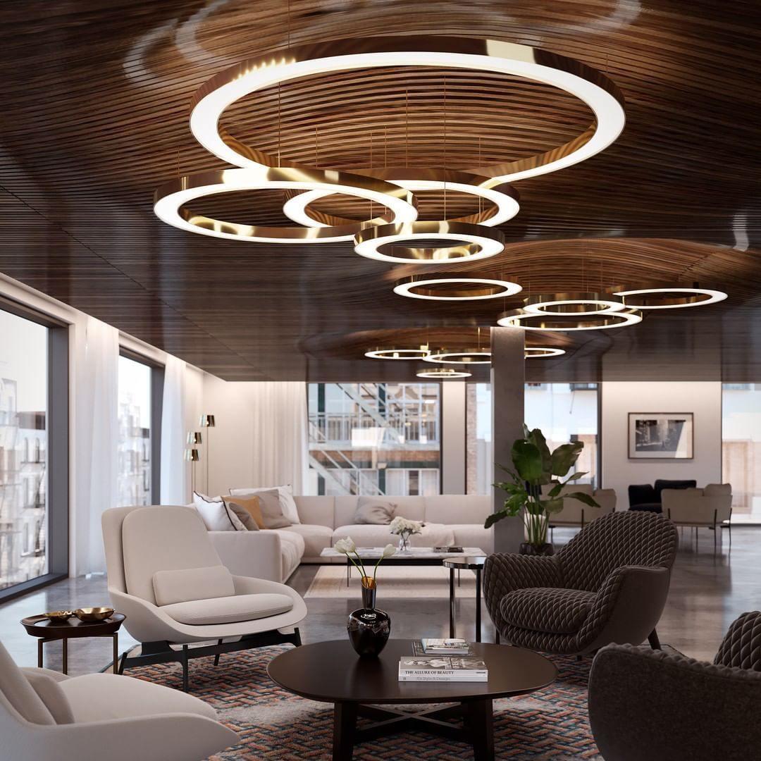 A large white ring ringed by smaller gold rings hangs under a timber-slat ceiling over a lounge of cream chairs, in a Clérachic setting.
