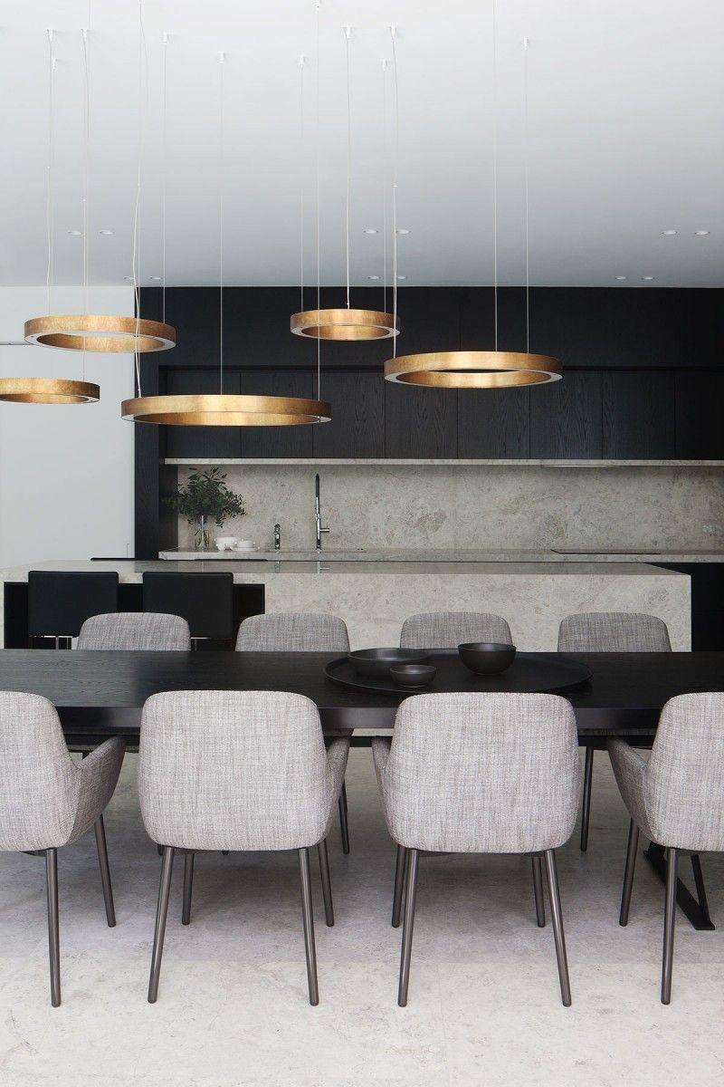 Five flat gold rings hang at varied heights above a long black dining table with grey upholstered chairs, lit by this Clérachic ring pendant.