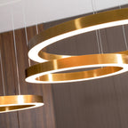Close view of brushed gold ring edges with the white glow of the diffuser, against a walnut-slat wall, on this Clérachic ring pendant.
