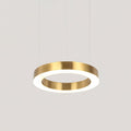 A single brushed gold ring pendant lit from inside, hanging on thin cables against a pale grey backdrop, a Clérachic ring light.