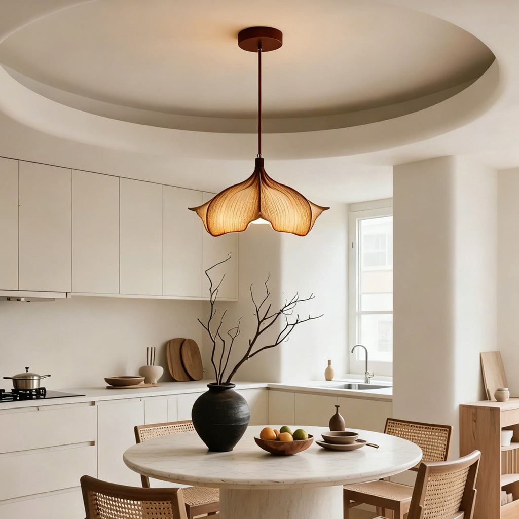 A Clérachic petal pendant hung from a rust-brown canopy in a round-ceilinged kitchen with a round table below.