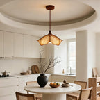 A Clérachic petal pendant hung from a rust-brown canopy in a round-ceilinged kitchen with a round table below.
