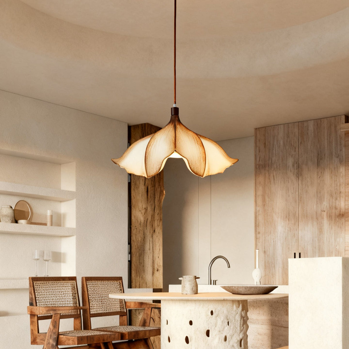 A Clérachic petal-shaped pendant above a kitchen island with rattan chairs and a rough timber post at one side.
