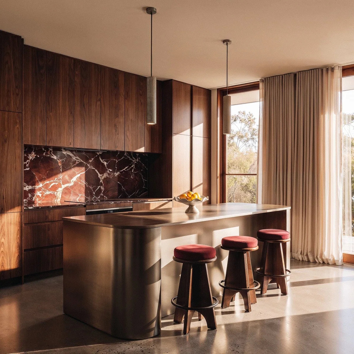 Clérachic two slim grey concrete cylinder pendant lights hung over a steel kitchen island with velvet-topped stools.