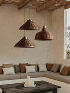 Three woven rattan pendants at staggered heights from this Clérachic fixture hang above a sectional sofa.