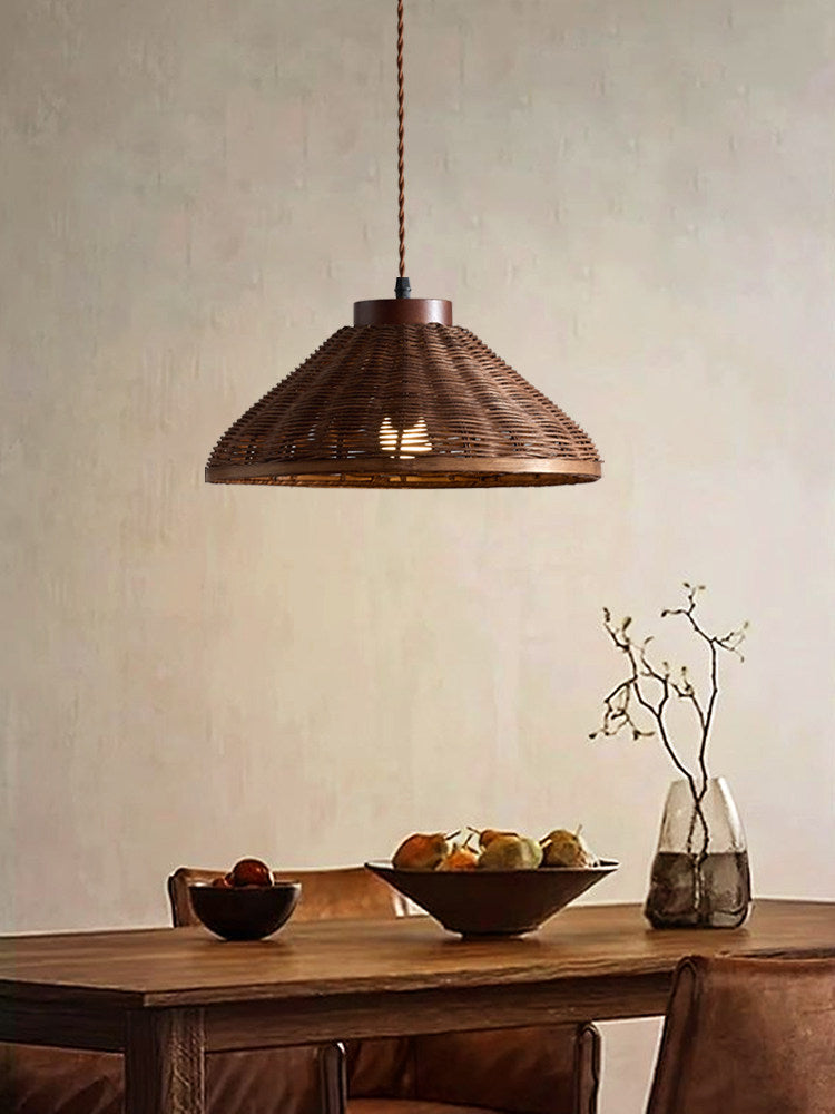 A single woven rattan pendant from this Clérachic fixture hangs above a wooden dining table with bowls of fruit.