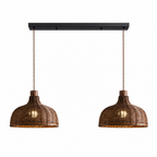 Two rounded rattan dome shades hang from this Clérachic pendant's black linear bar, set against a plain backdrop.