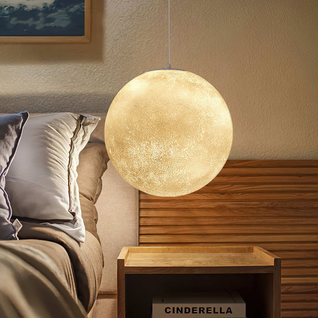 Lit glowing sphere from Clérachic beside a bed with a slatted wood headboard, soft light picking out the crater-like surface.