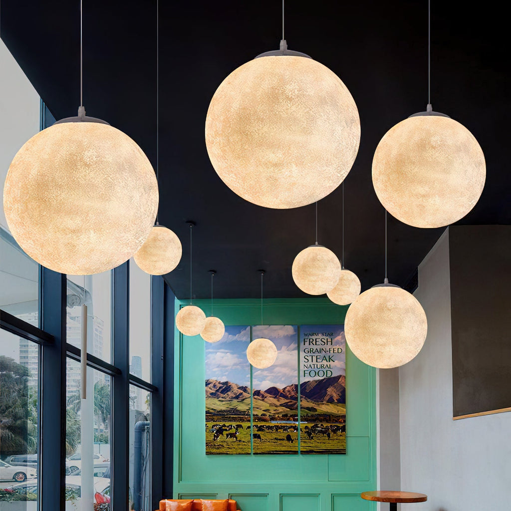 Several Clérachic spheres in different sizes hang at varied heights beside tall windows, a green wall and a framed landscape behind them.