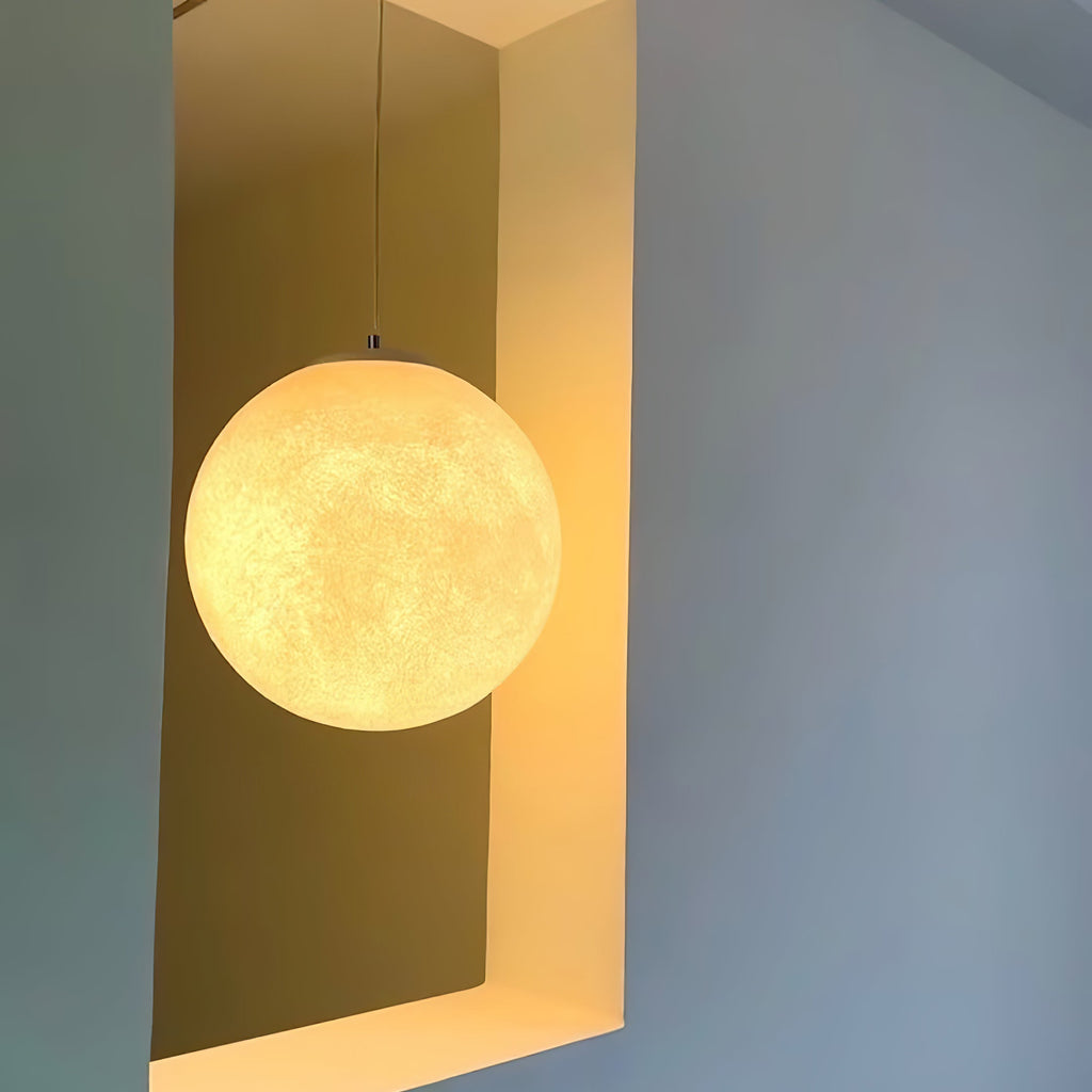 Seen against a pale blue wall, this Clérachic sphere glows golden in a recessed yellow niche, hung from a slim grey cord.