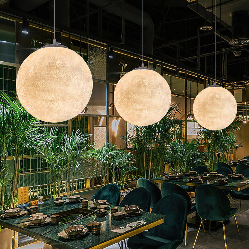 Three large Clérachic spheres in warm white hang over dining tables set among palms and green velvet chairs.