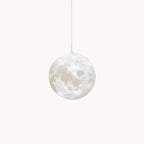 A cratered, moon-print globe pendant, shown for Clérachic, hangs from a thin cord on a plain white backdrop, unlit.