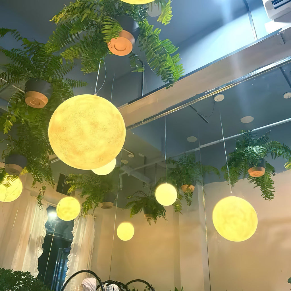 Golden-lit Clérachic spheres of mixed sizes hang among trailing ferns and potted plants beneath a high ceiling.