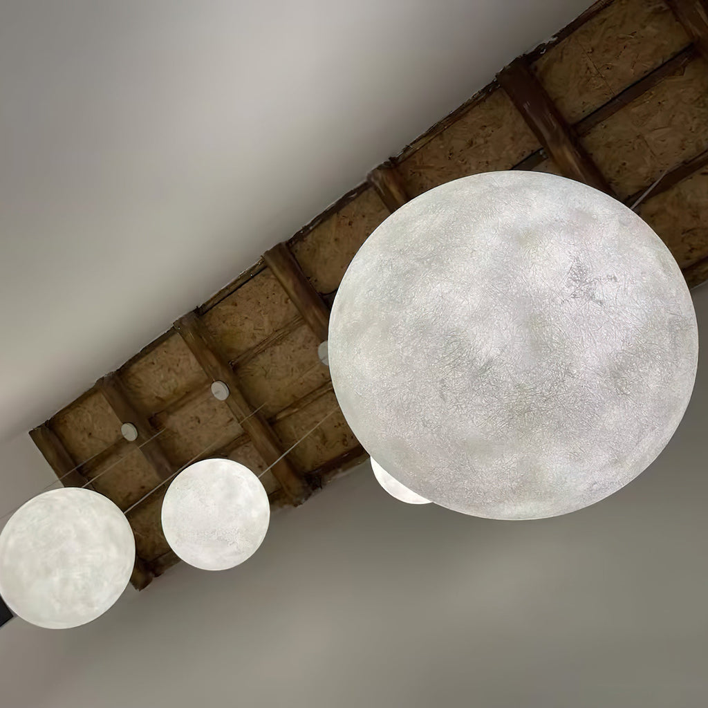 Underside view of a big white Clérachic sphere and two smaller ones hanging beneath a rough timber-panelled ceiling.
