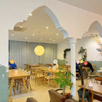 One Clérachic sphere with a soft yellow glow hangs in the middle of a bright dining room under an arched white ceiling.